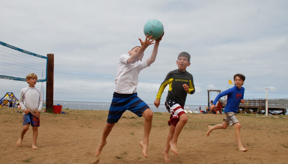 boy catching a ball over his shoulder being chased by another boy